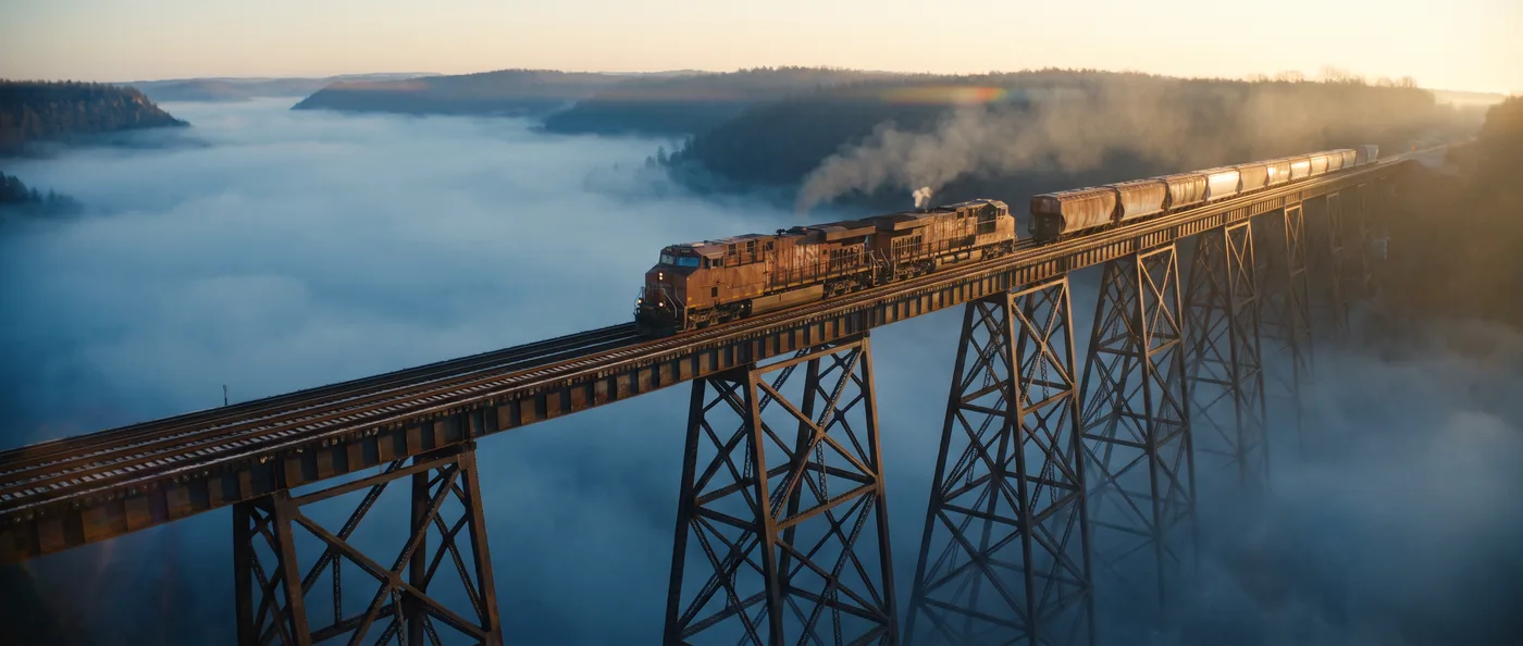 Nano Banana Pro Official 21:9 cinematic frame of a freight train crossing a trestle above fog